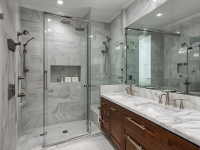 After renovation: modern luxury bathroom with marble surfaces, custom cabinetry, and spacious walk-in shower