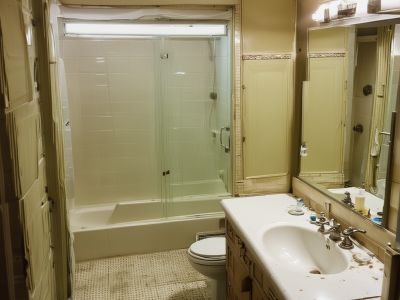 Before renovation: outdated 1970s bathroom with worn fixtures, basic tiles, and poor lighting